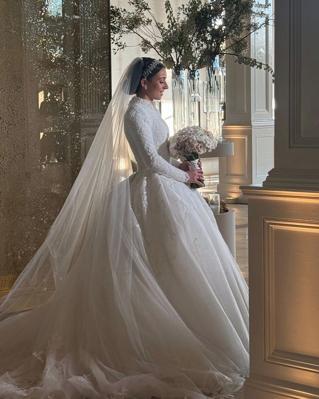 Bride in a cathedral-length gown beside a sunlit window