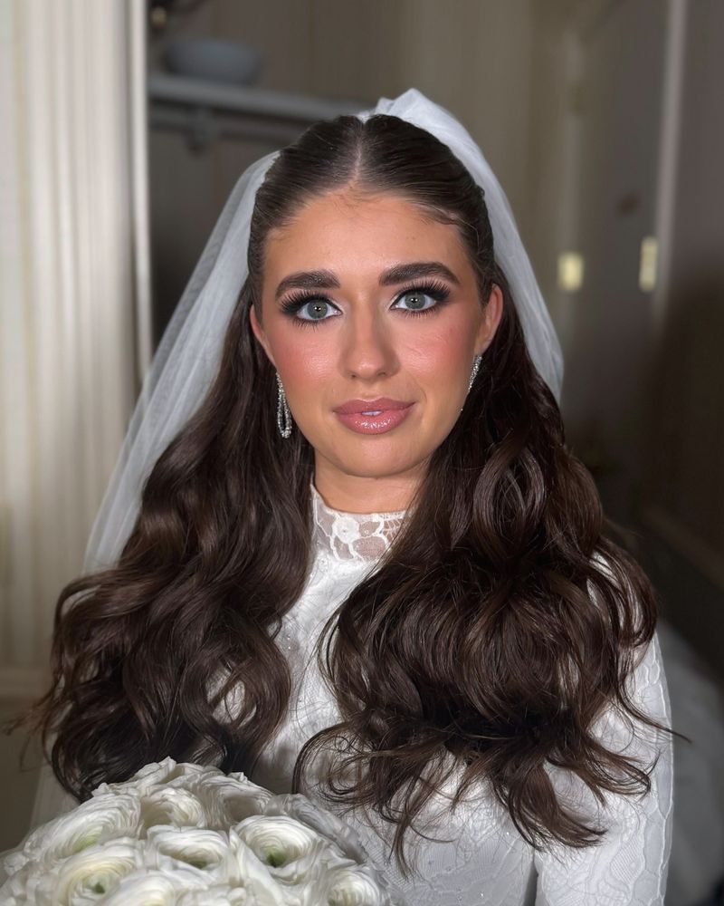 Bride with a lace gown and a bouquet of white and purple blooms