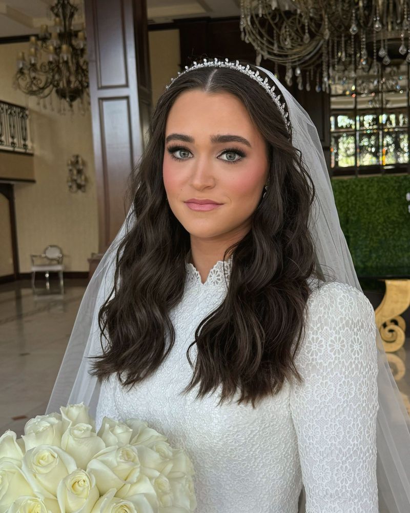 Bride holding white roses beneath a crystal chandelier