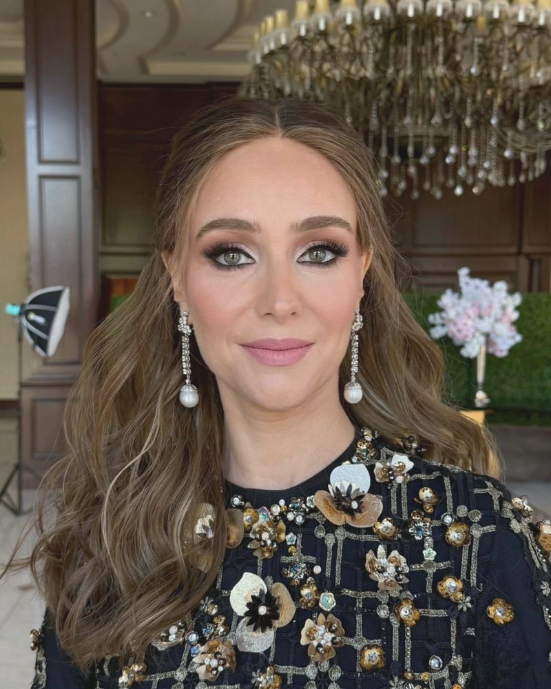 Evening glam with an embellished black gown under a chandelier