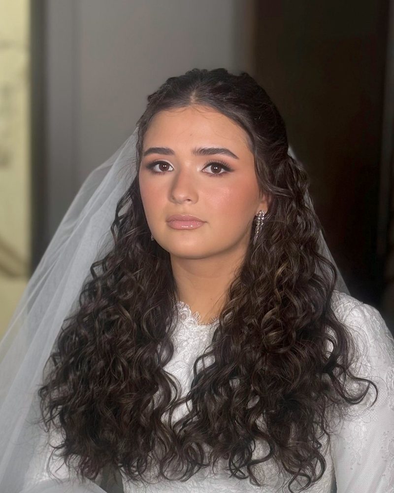 Bride with long dark curls, sheer veil and soft glam