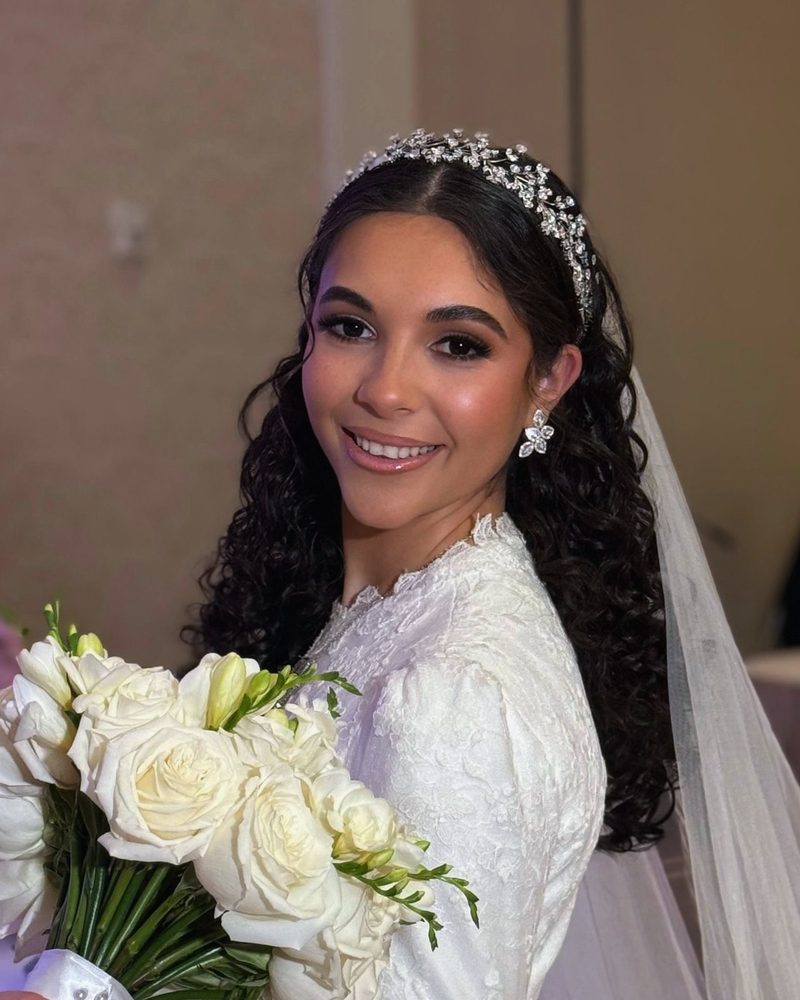 Smiling bride with a crystal tiara and a bouquet of roses
